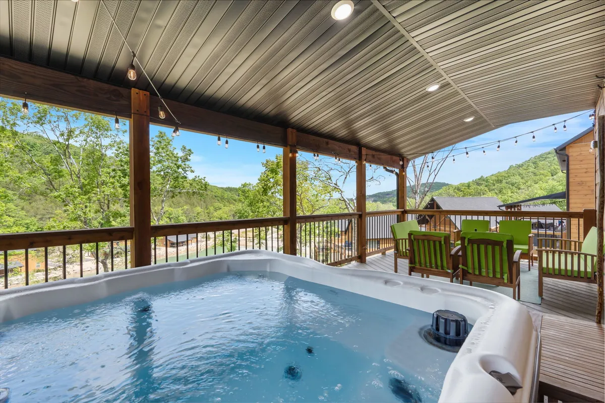 This image features an exterior deck with a private hot tub, outdoor seating area, and sweeping mountain views in the background. The atmosphere is inviting and tranquil, ideal for relaxing and socializing while surrounded by nature.