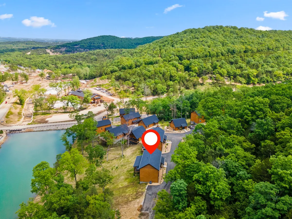A serene cluster of rustic cabins sits by a shimmering lake surrounded by lush greenery. The tranquil setting invites outdoor activities, with open space for hiking, fishing, and wildlife watching. Golden sunrise reflections dance on the calm water, suggesting early-morning adventures or peaceful family moments by the shore.