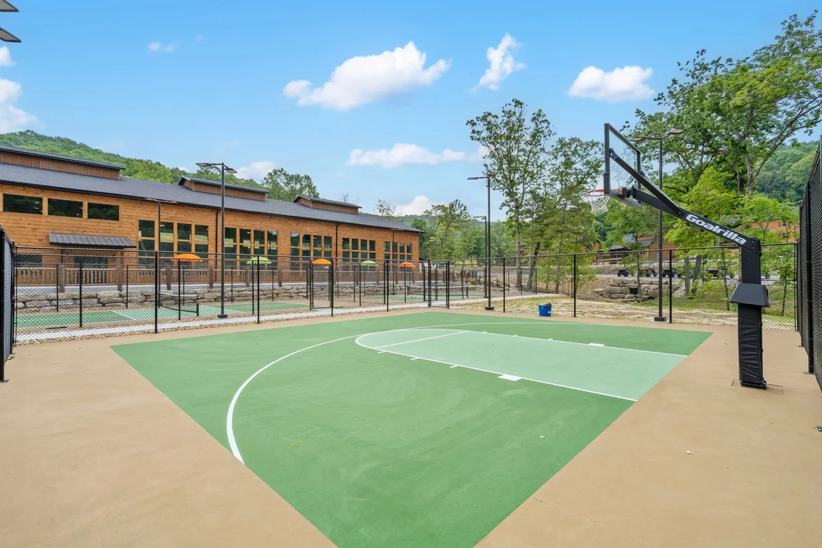 A modern basketball court is nestled among tall trees, with a building facade in the background. The space is designed for active play and friendly competition, creating a vibrant hub for family gatherings and outdoor excitement.