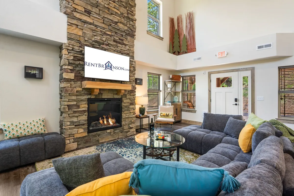 A cozy living room centered around a stone fireplace, featuring a large sectional sofa and a coffee table, with a wall-mounted TV for entertainment. The arrangement encourages both relaxation and socialization, perfect for family movie marathons or cheering on a favorite team.